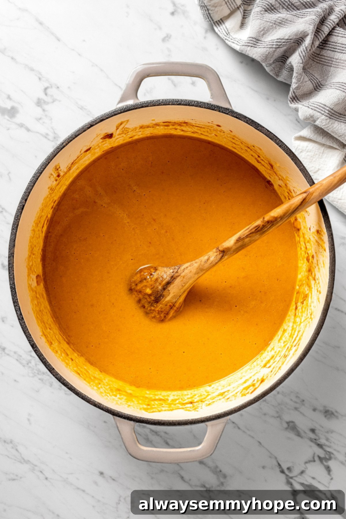 Vegan mulligatawny soup simmering in a Dutch oven with a wooden spoon resting in it.