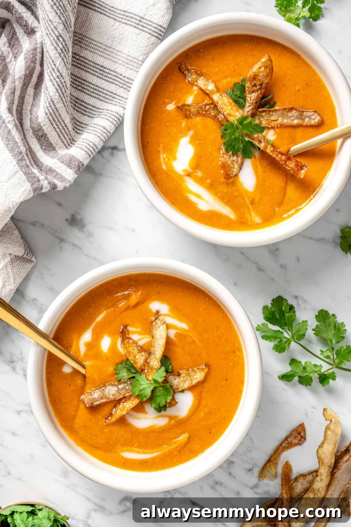 Two white bowls of vegan mulligatawny soup, garnished with herbs, on a wooden surface.