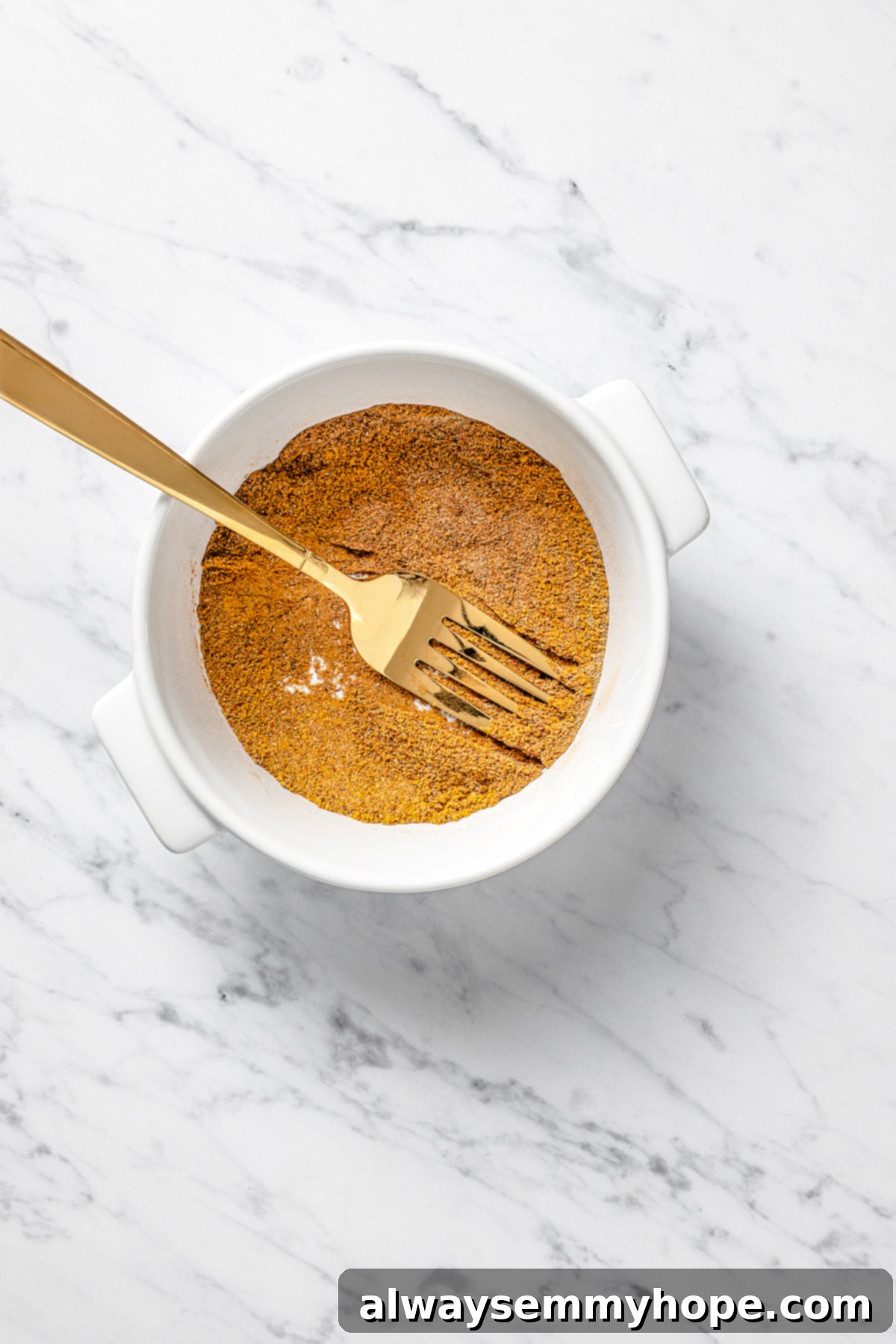 Overhead view of a small bowl filled with a vibrant mix of ground Indian spices.