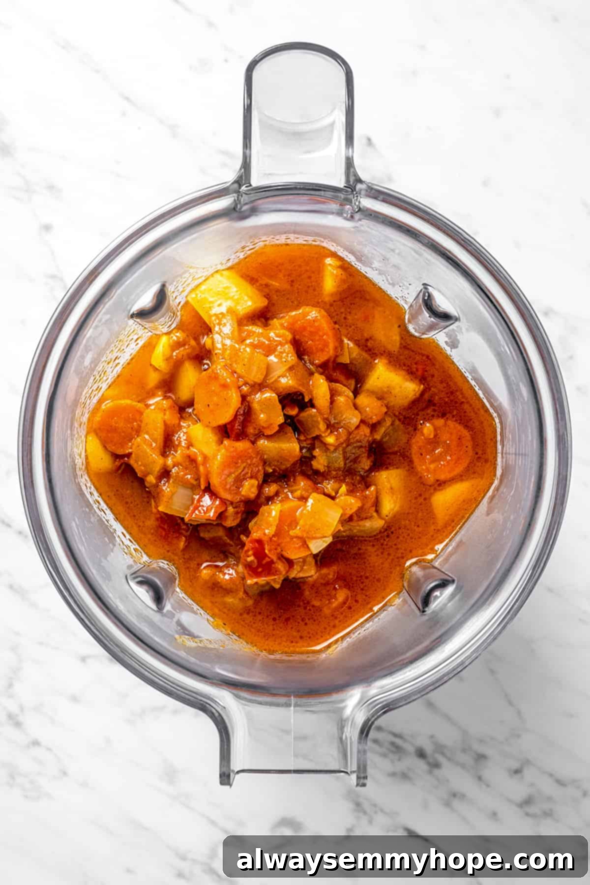 Cooked vegetables being transferred to a blender with vegetable broth.
