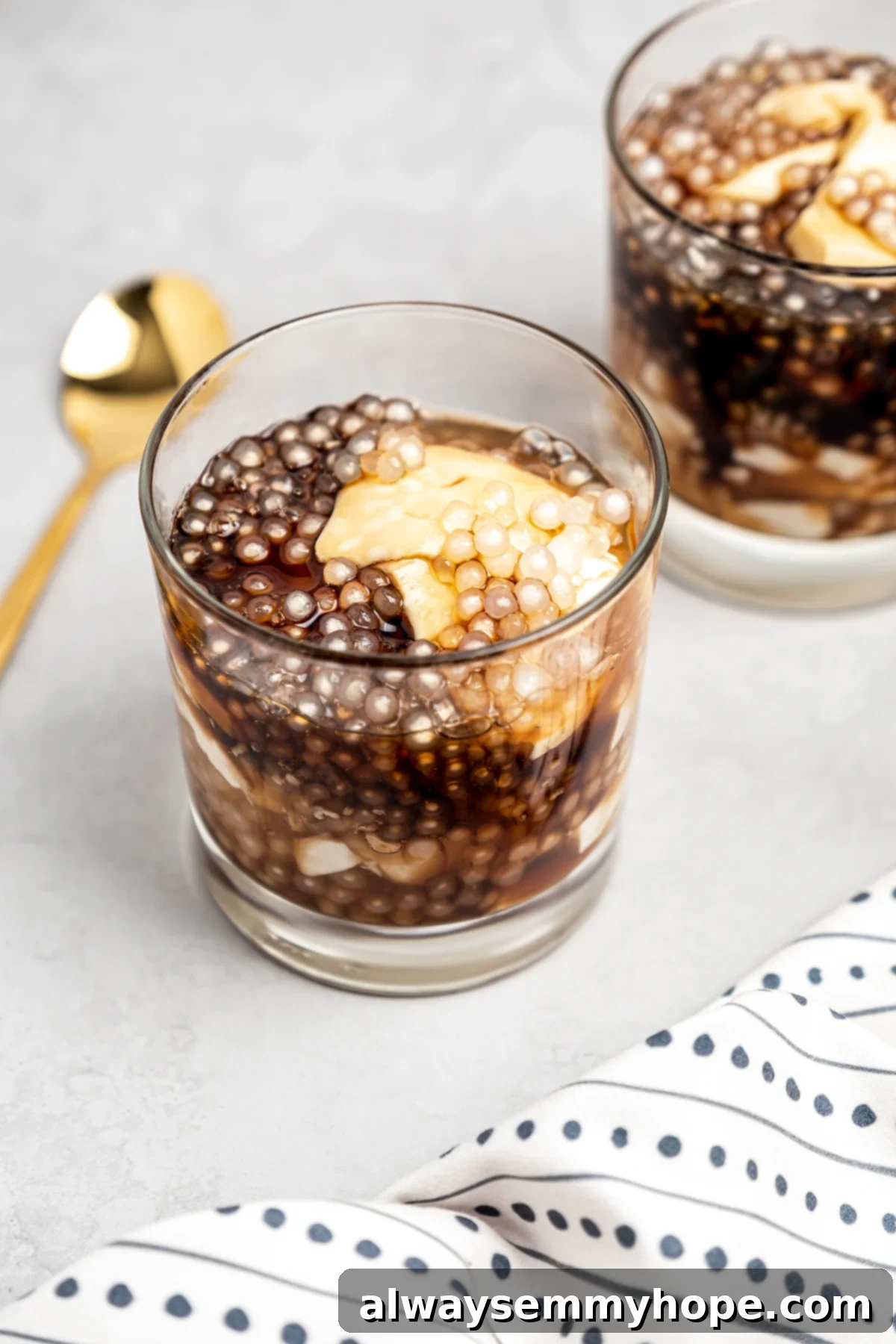 Two servings of taho in glasses with napkin and gold spoon