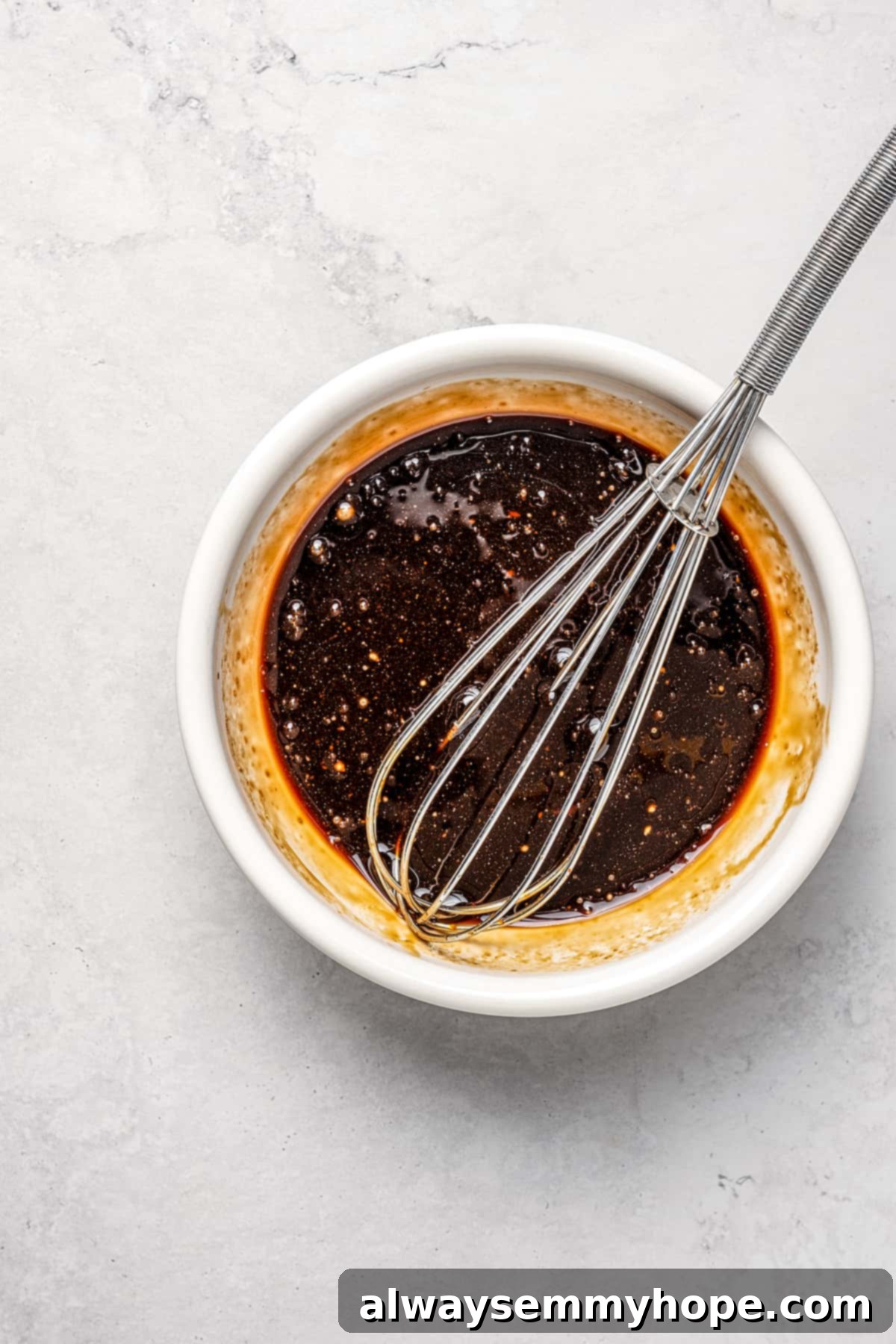 This vegan pad see ew pairs rice noodles, vegetables, and tofu with a sweet, savoury, and slightly tangy sauce for a restaurant-style meal! Overhead view of the vegan pad see ew sauce being whisked in a small bowl.