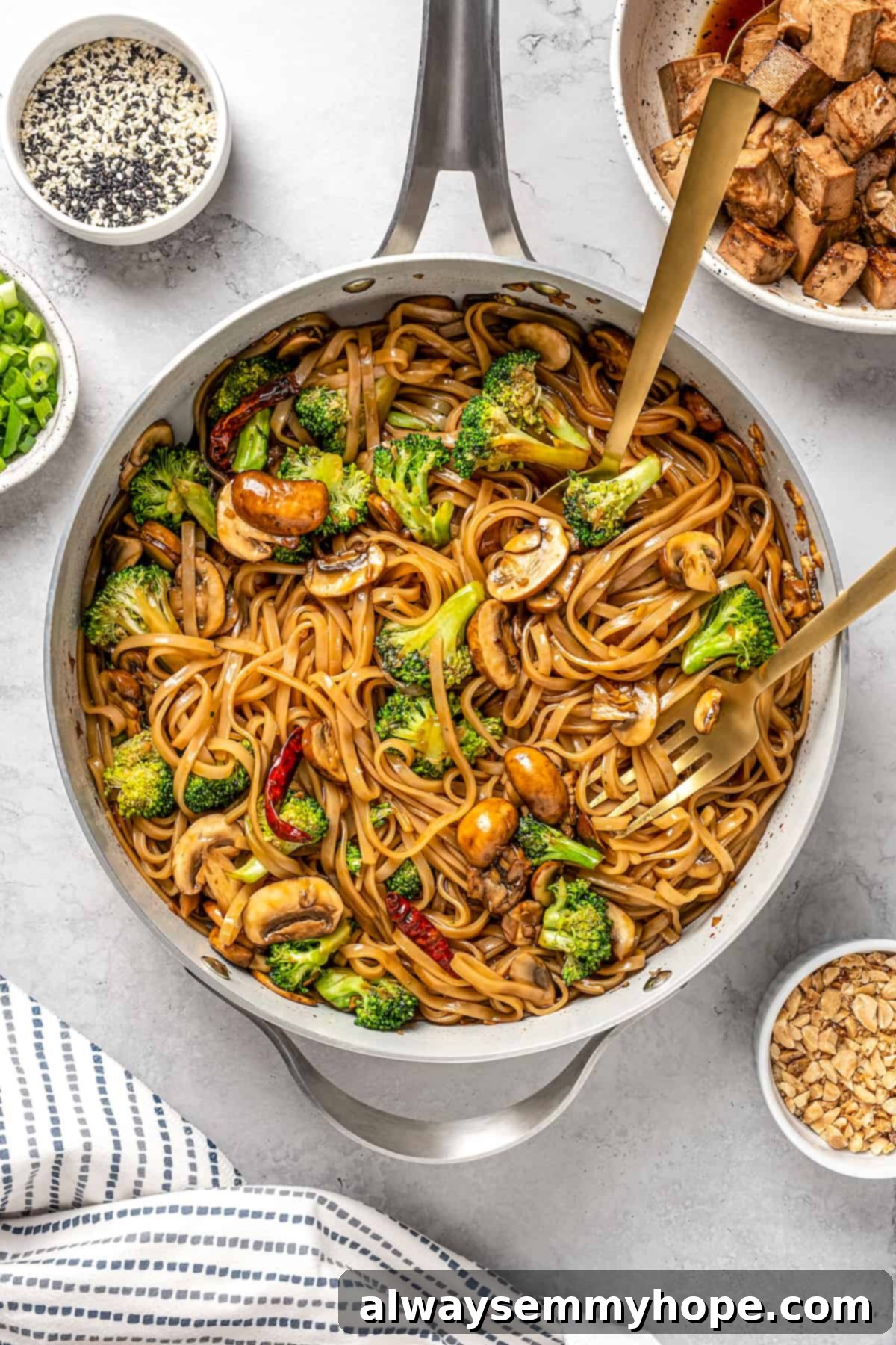 This vegan pad see ew pairs rice noodles, vegetables, and tofu with a sweet, savoury, and slightly tangy sauce for a restaurant-style meal! Overhead view of all ingredients for vegan pad see ew combined in the skillet, coated in the sauce, and finishing cooking.