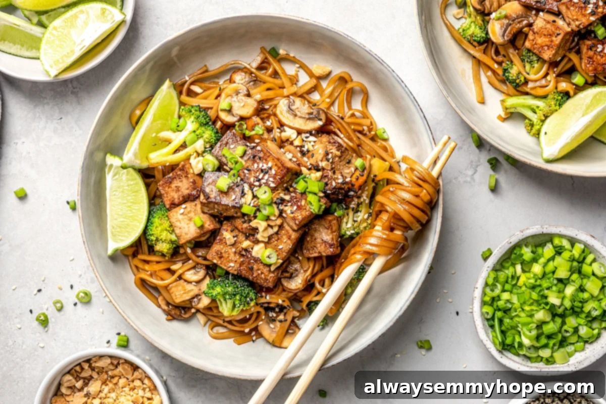 This vegan pad see ew pairs rice noodles, vegetables, and tofu with a sweet, savoury, and slightly tangy sauce for a restaurant-style meal! Close-up of vegan pad see ew in a bowl with chopsticks, showing the glossy noodles and various ingredients.