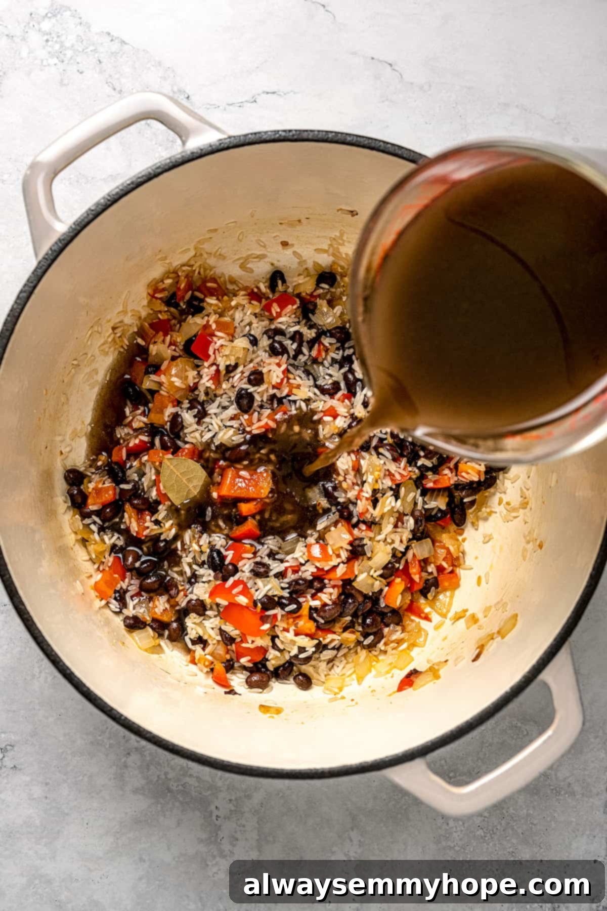 Pouring bean broth into pot of Cuban rice and beans