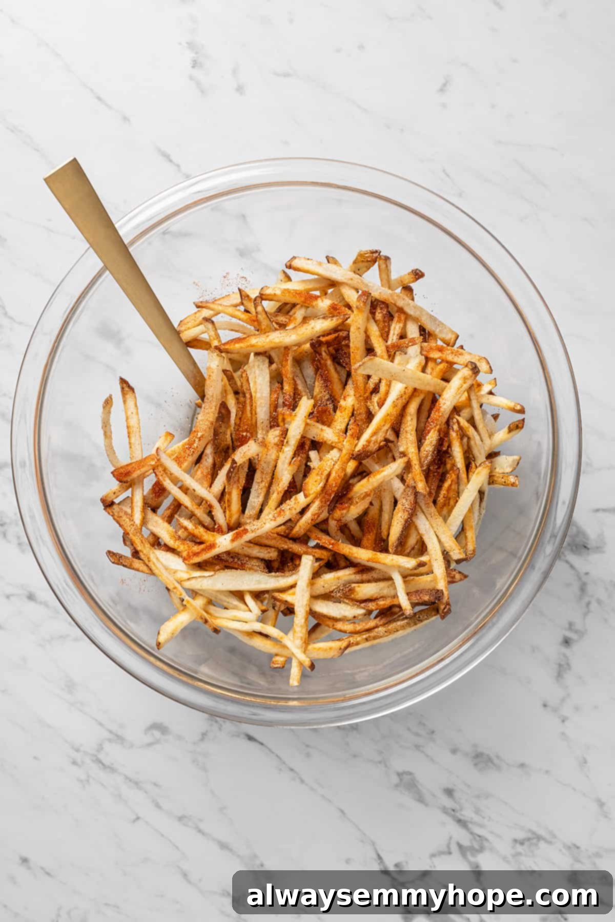 The air fryer makes these shoestring fries perfectly crispy without all the oil, and my blend of savoury seasonings makes them irresistible! Overhead view of cooked fries in glass mixing bowl