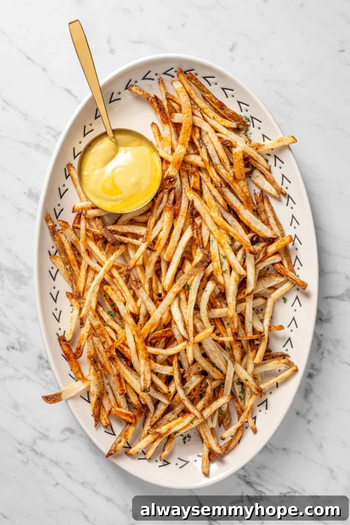 The air fryer makes these shoestring fries perfectly crispy without all the oil, and my blend of savoury seasonings makes them irresistible! Overhead view of air fryer shoestring fries on platter with dipping sauce