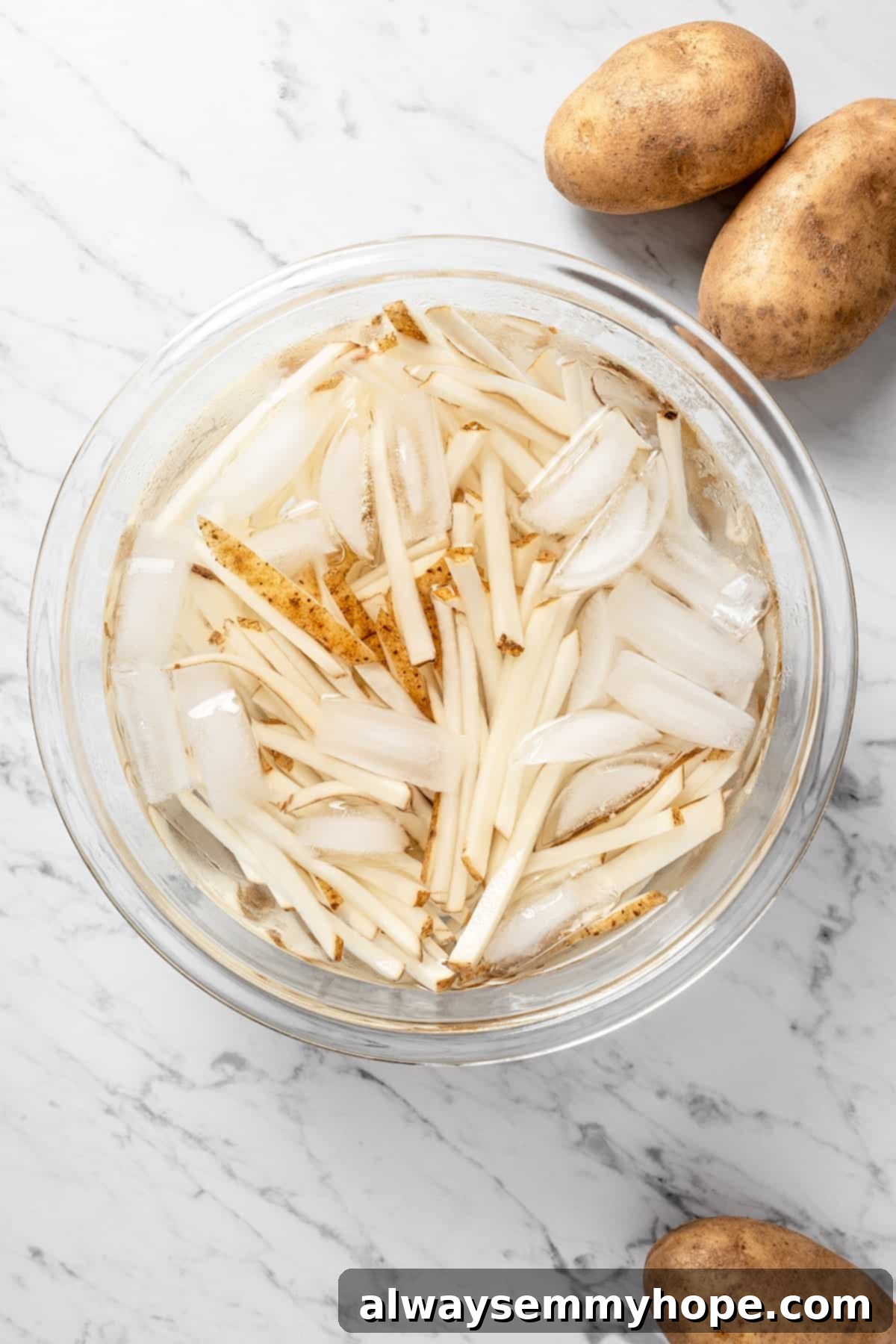 The air fryer makes these shoestring fries perfectly crispy without all the oil, and my blend of savoury seasonings makes them irresistible! Overhead view of soaking fries in ice water