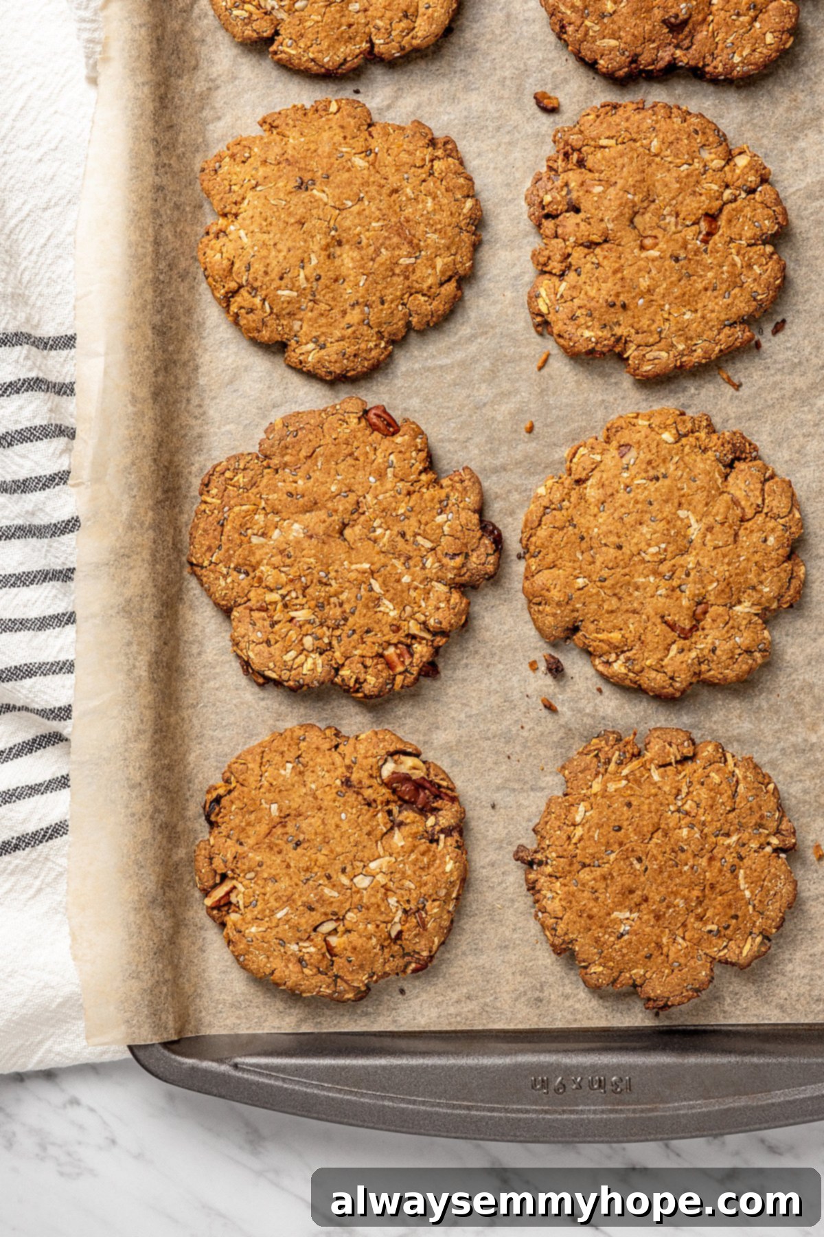Freshly Baked Vegan Lactation Cookies Cooling Overhead view of freshly baked vegan lactation cookies cooling on a parchment-lined baking sheet, golden-brown and slightly spread.