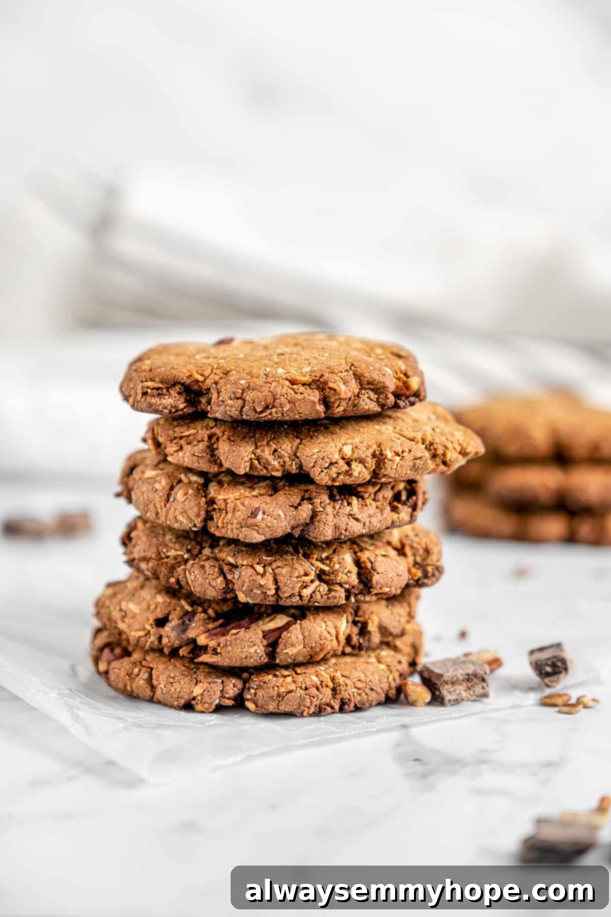 A Delicious Display of Homemade Vegan Lactation Cookies A beautifully arranged stack of six vegan lactation cookies, with additional cookies artfully blurred in the background, highlighting their delicious texture and chocolate chips.