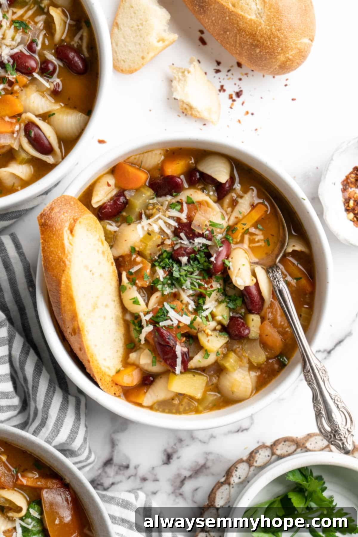 This vegetable minestrone soup is hearty comfort food at its best! Load it with veggies, beans, and pasta and enjoy a cozy one-pot meal. Overhead view of bowl of minestrone soup with spoon and slice of bread