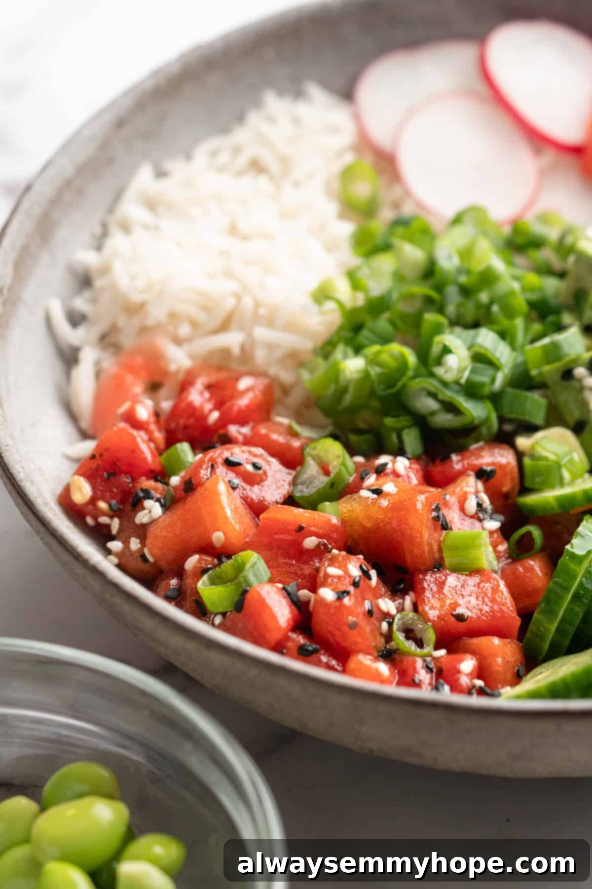 Transform your plant-based meals with this incredible watermelon tuna, perfectly capturing the essence of ahi for your favorite poke bowls and more. Close-up of vibrant vegan watermelon tuna nestled among other fresh ingredients in a poke bowl, showcasing its realistic texture and color.
