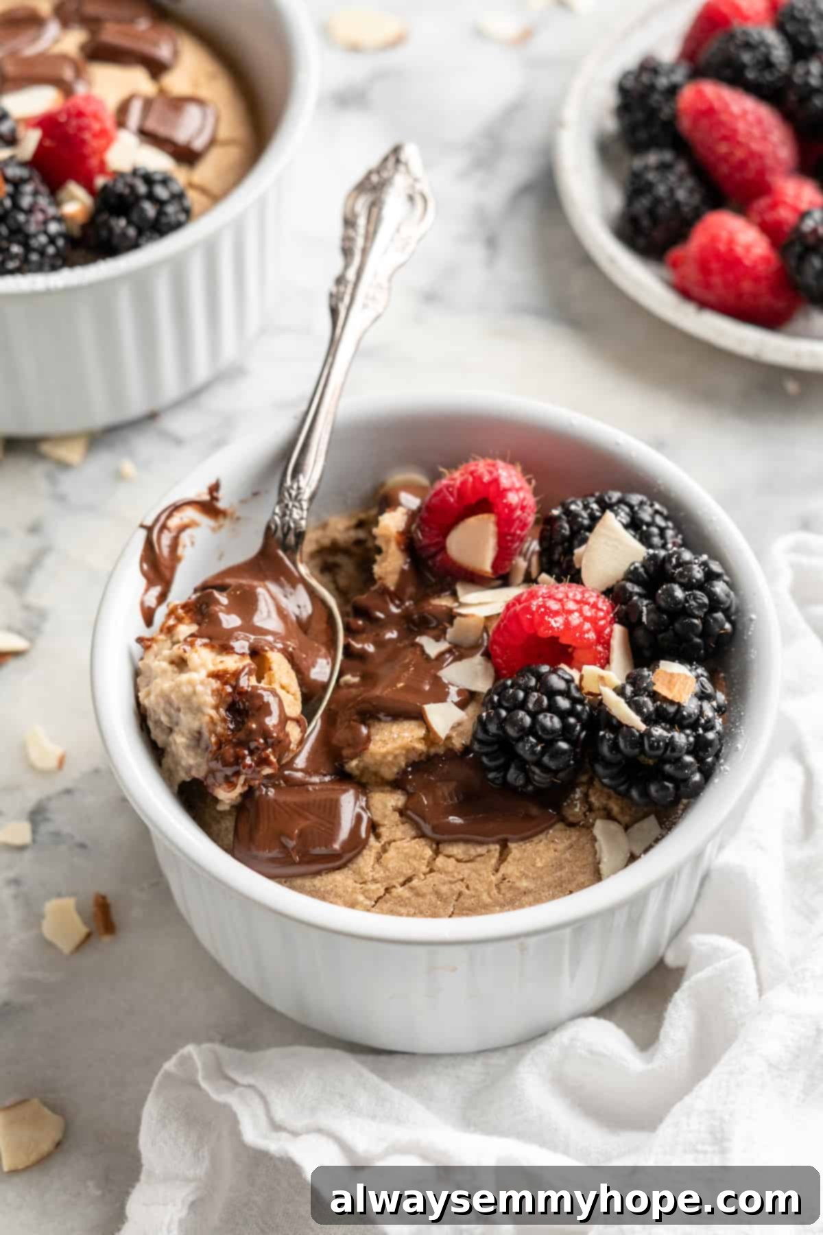 These TikTok vegan baked oats are a filling breakfast, with just a little bit of decadence thanks to the addition of dark chocolate. So easy! Ramekin of vegan baked oats topped with melted chocolate, berries, and almonds