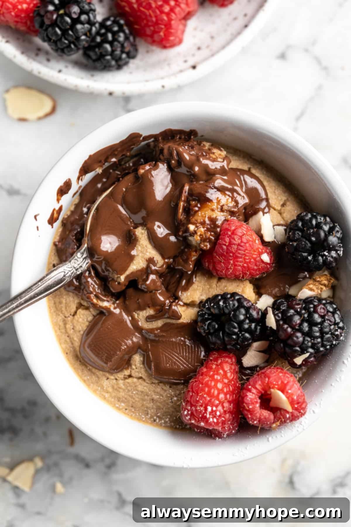 These TikTok vegan baked oats are a filling breakfast, with just a little bit of decadence thanks to the addition of dark chocolate. So easy! Overhead view of vegan baked oats topped with berries and chocolate, with spoon scooping into oats