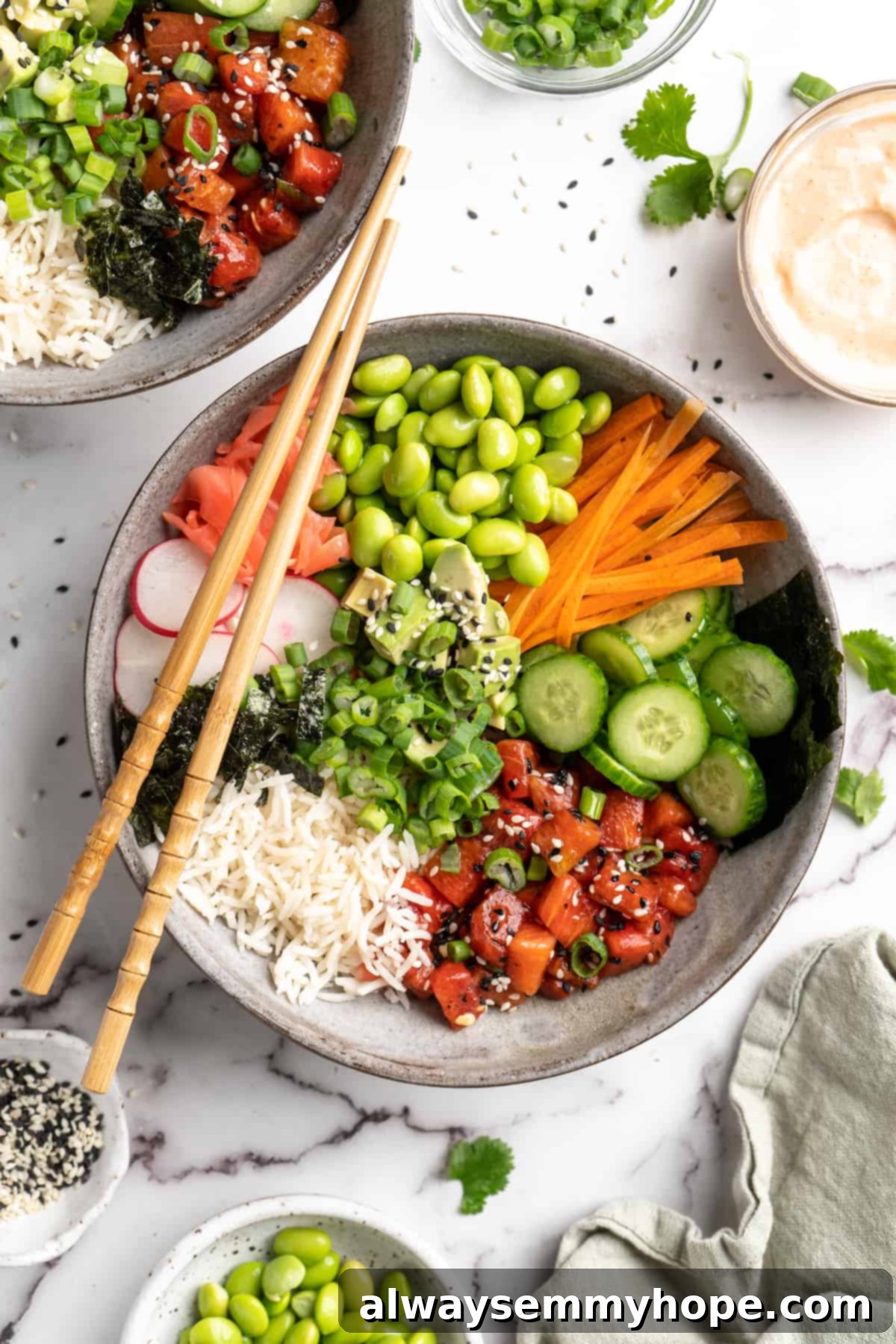 These easy vegan poke bowls are full of colour and flavour! Top a base of rice with watermelon tuna and an array of fresh toppings. So good! Overhead view of vegan poke bowl with chopsticks on top, surrounded by toppings and garnishes, highlighting fresh ingredients and vibrant colors