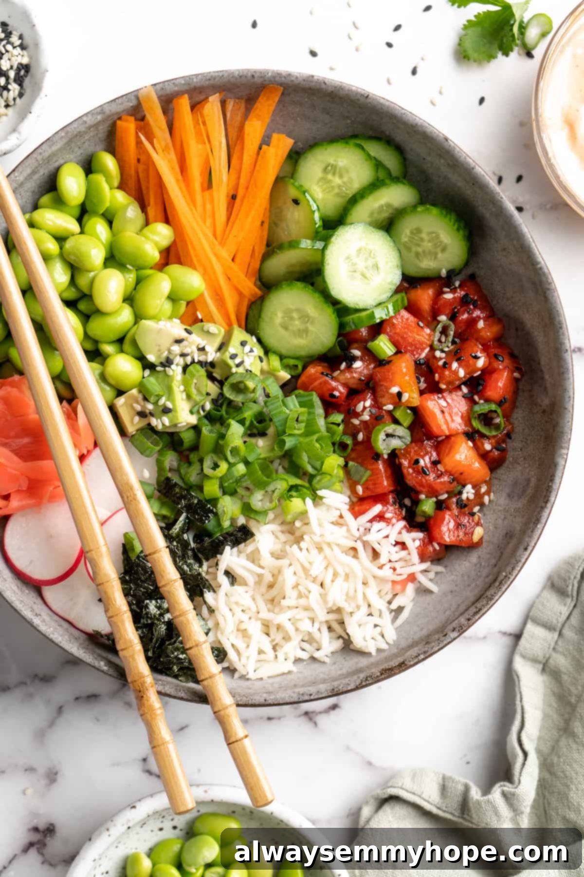 These easy vegan poke bowls are full of colour and flavour! Top a base of rice with watermelon tuna and an array of fresh toppings. So good! Overhead view of vegan poke bowl with chopsticks set on top, ready for eating