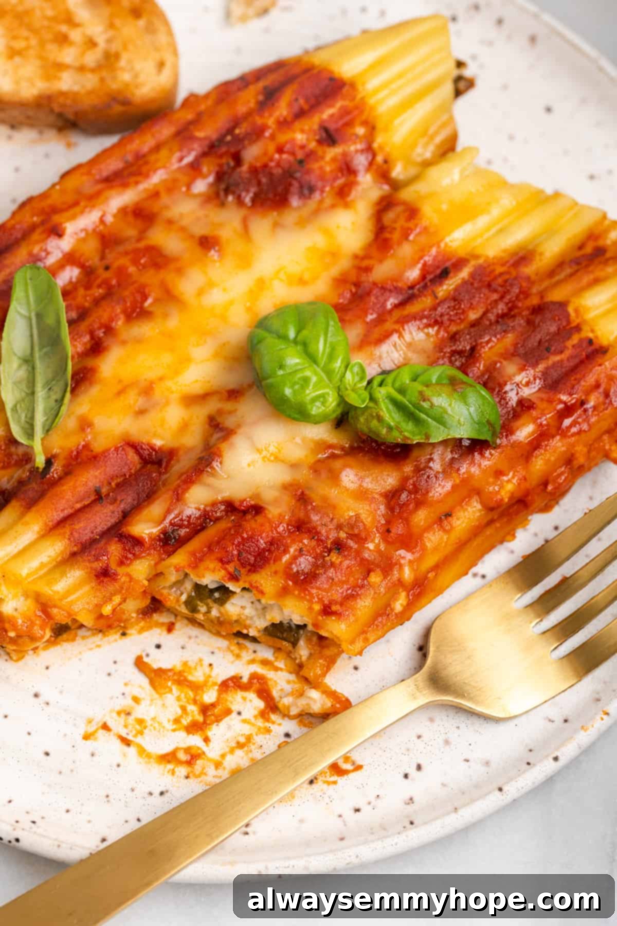 Close-up of a bite of vegan manicotti, showcasing the rich filling. A forkful of vegan manicotti with a delicious bite removed, revealing the creamy spinach and ricotta filling.