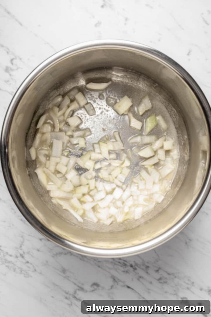 Overhead view of thinly sliced yellow onions cooking in melted vegan butter in the Instant Pot insert on sauté mode