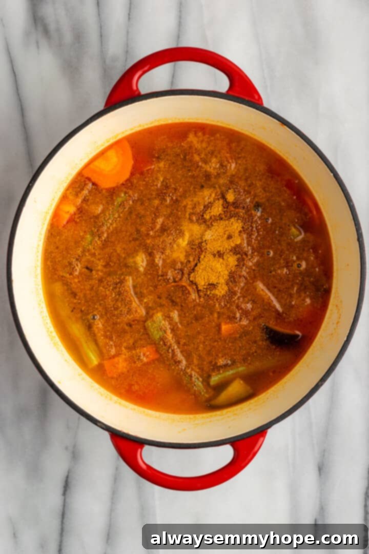 This vegan sambar is just like the sambar at your favourite Indian restaurant! Here's how to make this hearty lentil and veggie stew at home. Overhead view of sambar in Dutch oven, after adding spices