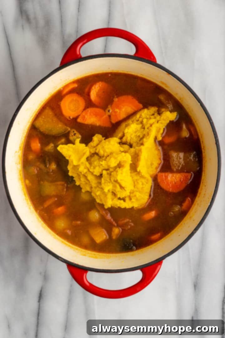 This vegan sambar is just like the sambar at your favourite Indian restaurant! Here's how to make this hearty lentil and veggie stew at home. Overhead view of pureed lentils being added to pot of sambar