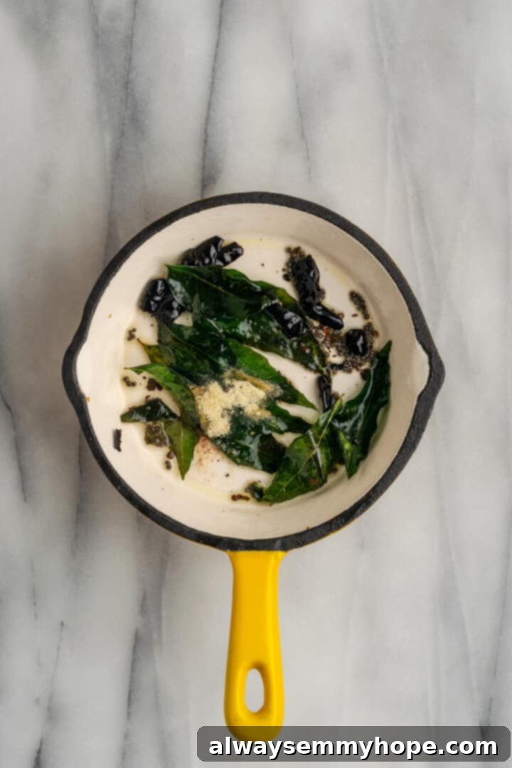 This vegan sambar is just like the sambar at your favourite Indian restaurant! Here's how to make this hearty lentil and veggie stew at home. Overhead view of tempering from sambar in small saucepan