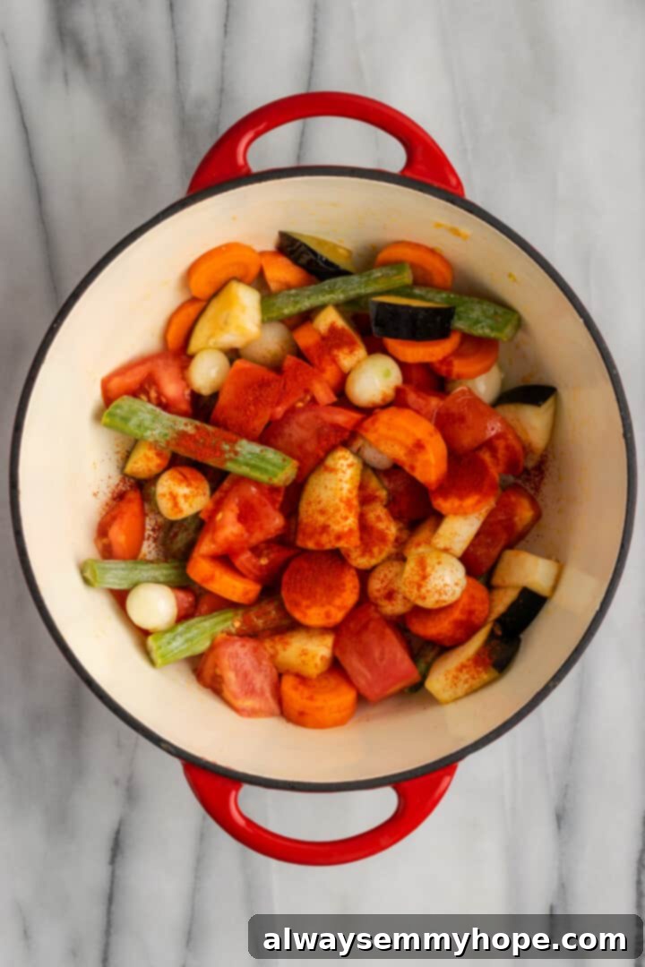 This vegan sambar is just like the sambar at your favourite Indian restaurant! Here's how to make this hearty lentil and veggie stew at home. Overhead view of vegetables and red chili powder in Dutch oven