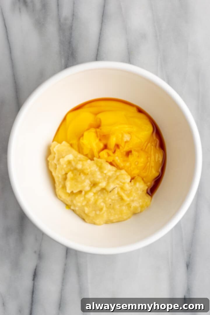 Mashed bananas, vanilla, and warm pudding combined in a mixing bowl
