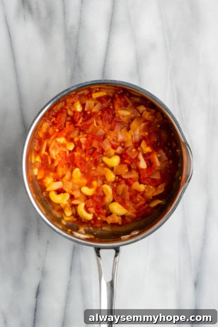 Overhead view of cooked cashews, tomatoes, and onions for malai kofta sauce