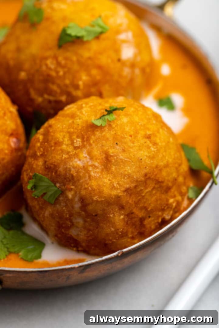 Closeup of malai kofta dumpling in bowl with sauce