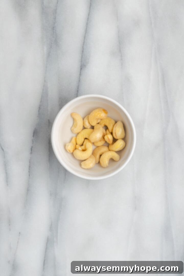 Overhead view of raw cashews soaking in water in small bowl