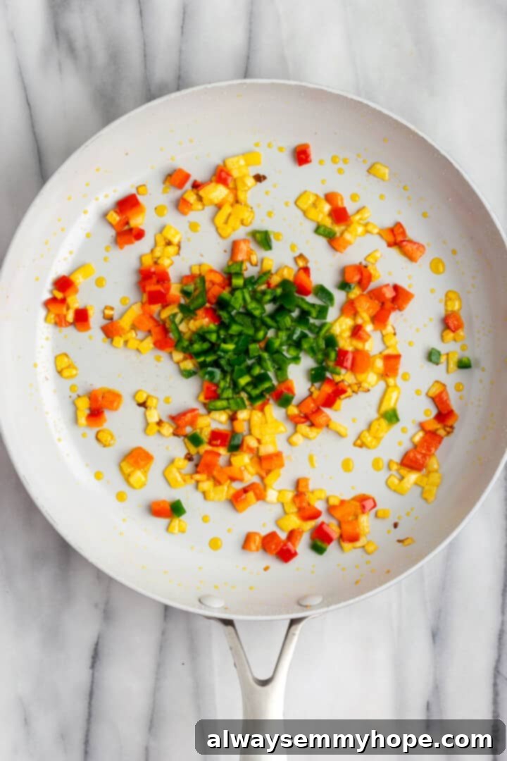 These crispy vegan southwest egg rolls are full of bold flavors and satisfying ingredients like vegan chicken, black beans, and veggies. Yum! Overhead view of corn and peppers cooking in skillet