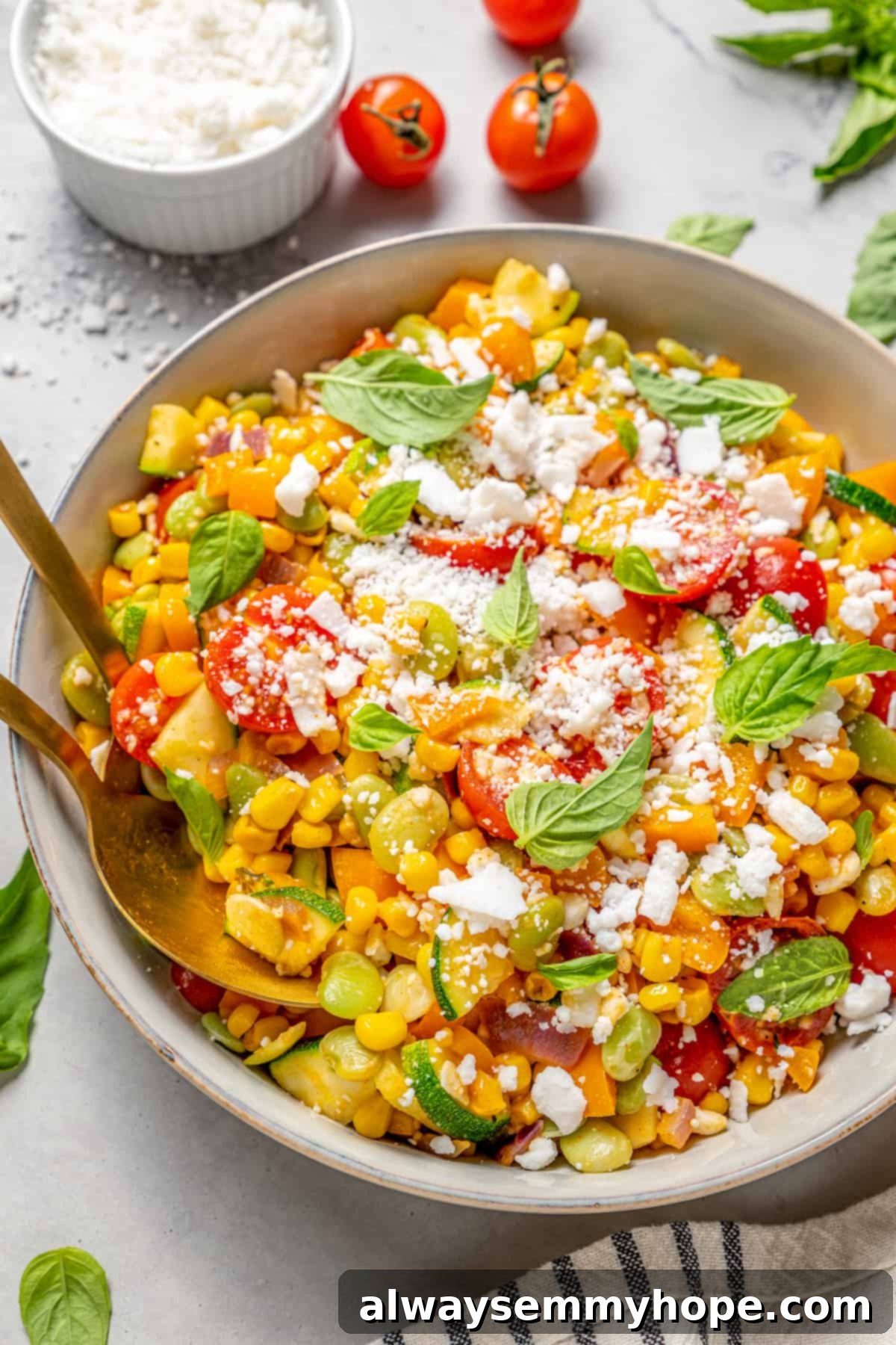 Gold spoons digging into bowl of vegan corn succotash