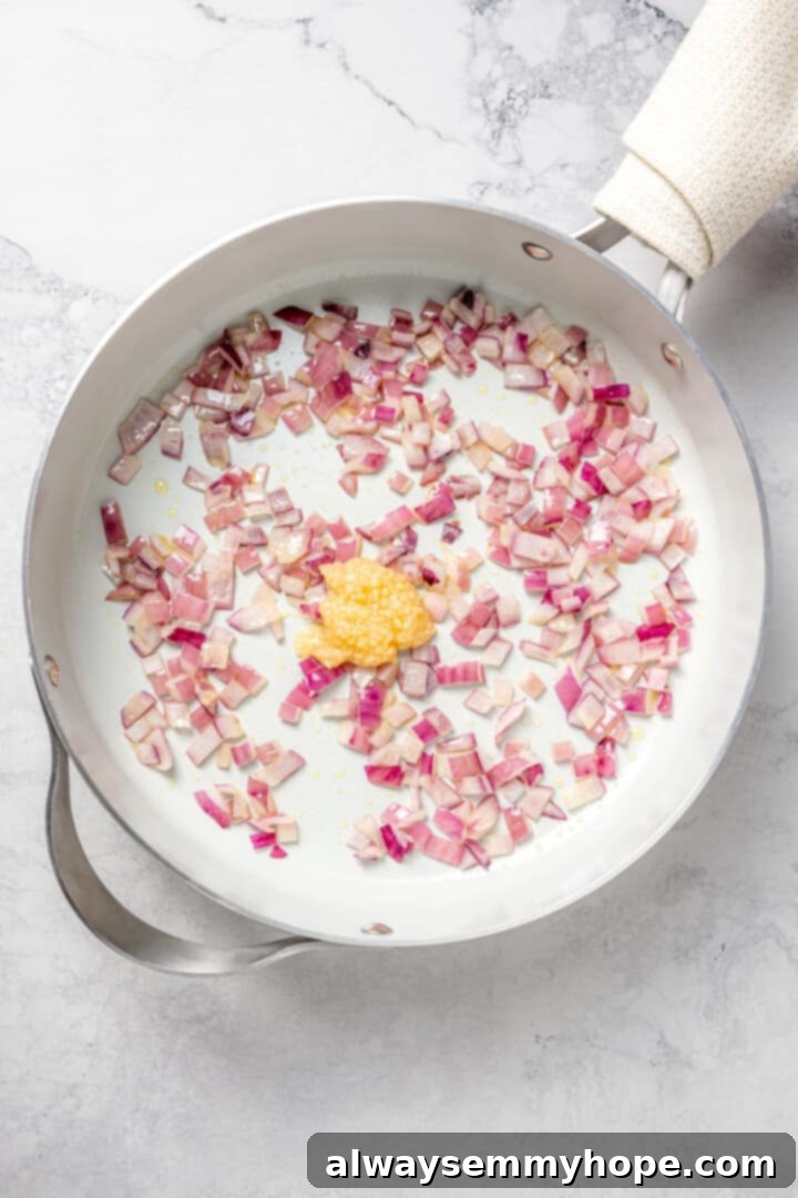 Overhead view of onions and garlic cooking in skillet