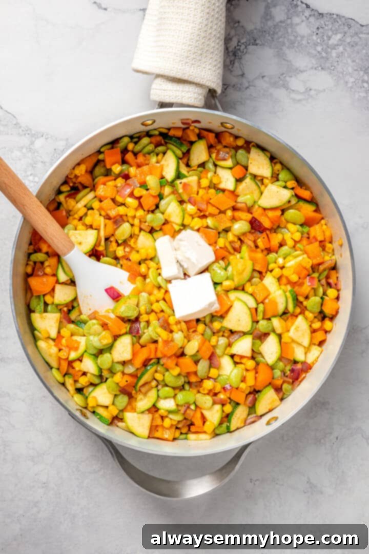 Overhead view of vegan corn succotash in skillet after adding feta