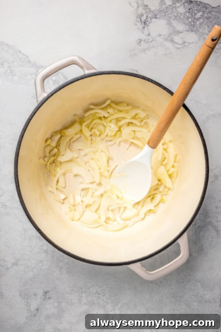 Sautéing Onions for Flavorful Biryani Base Thinly sliced yellow onions sautéing in a pot with a wooden spoon.