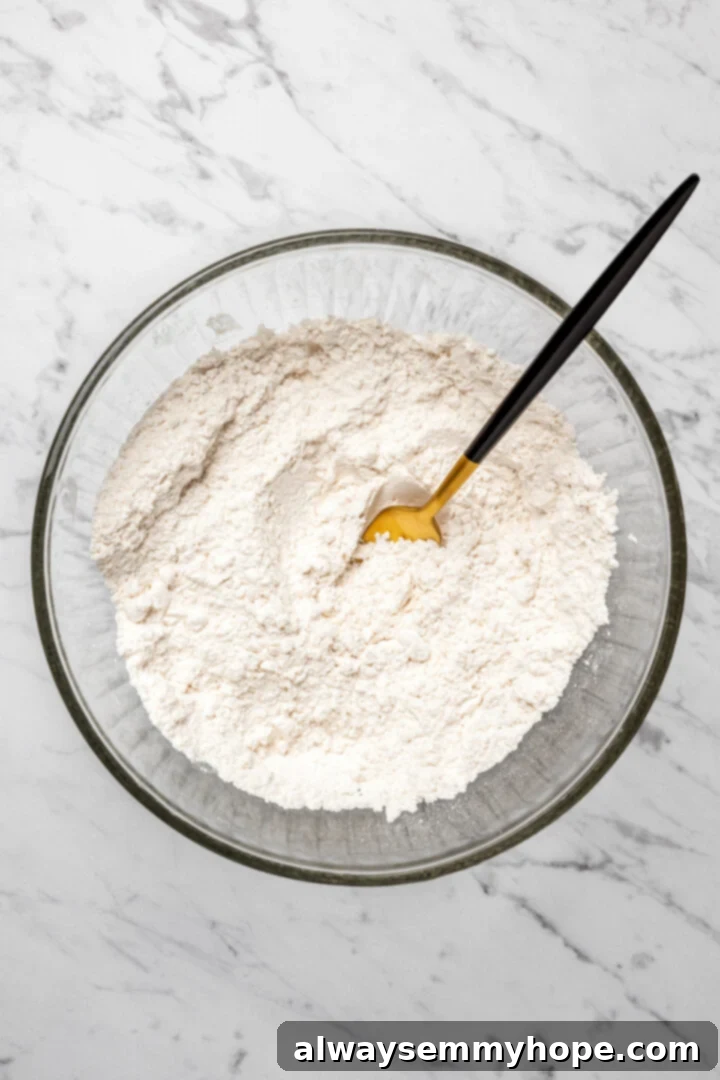 Overhead view of dry ingredients for dumplings in glass mixing bowl with fork