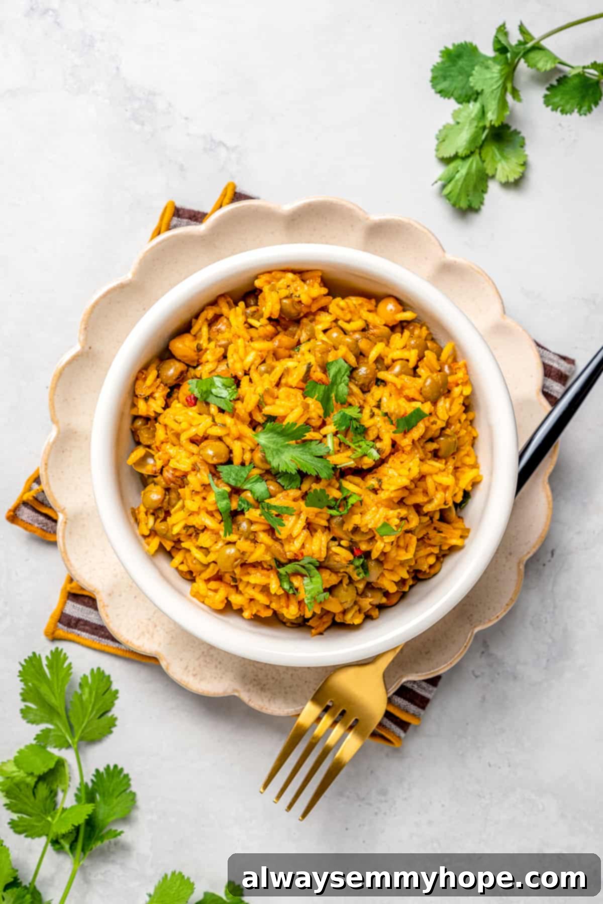Overhead view of a bowl of vegan Puerto Rican rice and beans, elegantly presented on a plate with a fork.