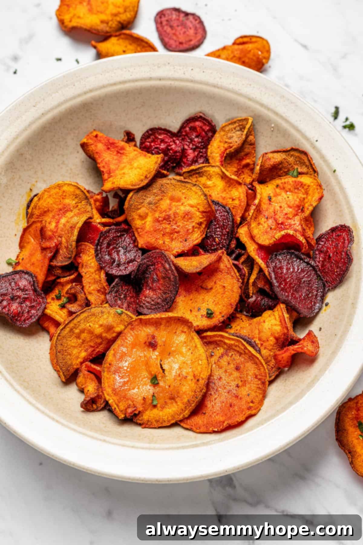 A shallow bowl generously filled with a vibrant assortment of crispy air fryer veggie chips, glistening slightly and invitingly presented.