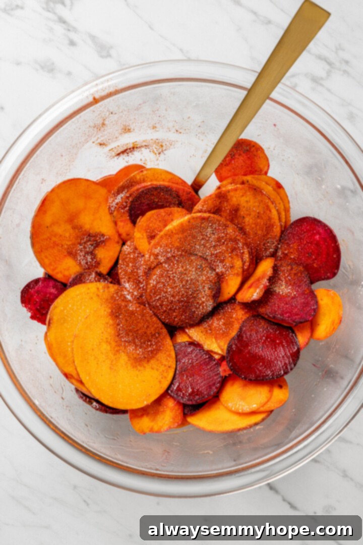 Sliced vegetables in a glass bowl, now drizzled with oil and seasoned with salt, pepper, and paprika, ready for their final toss.