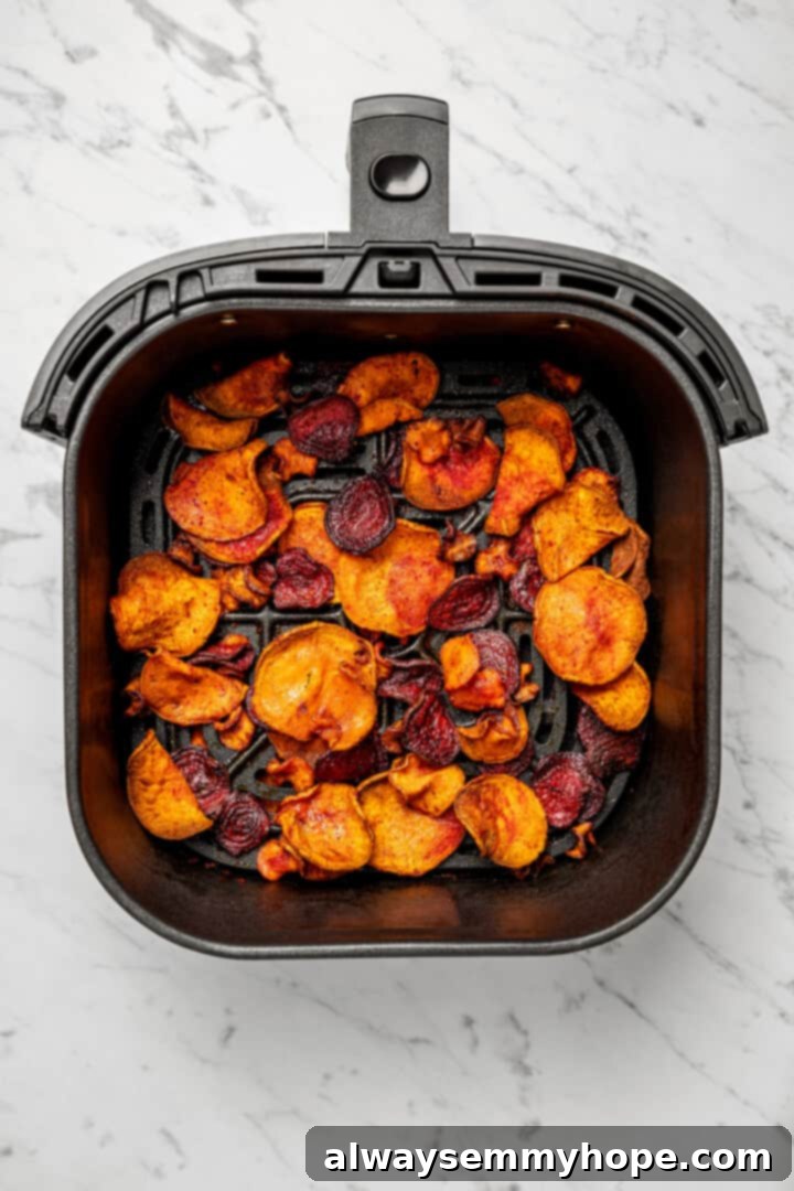 Golden-brown, crispy air fryer veggie chips filling the air fryer basket, indicating they are fully cooked and ready to be removed.