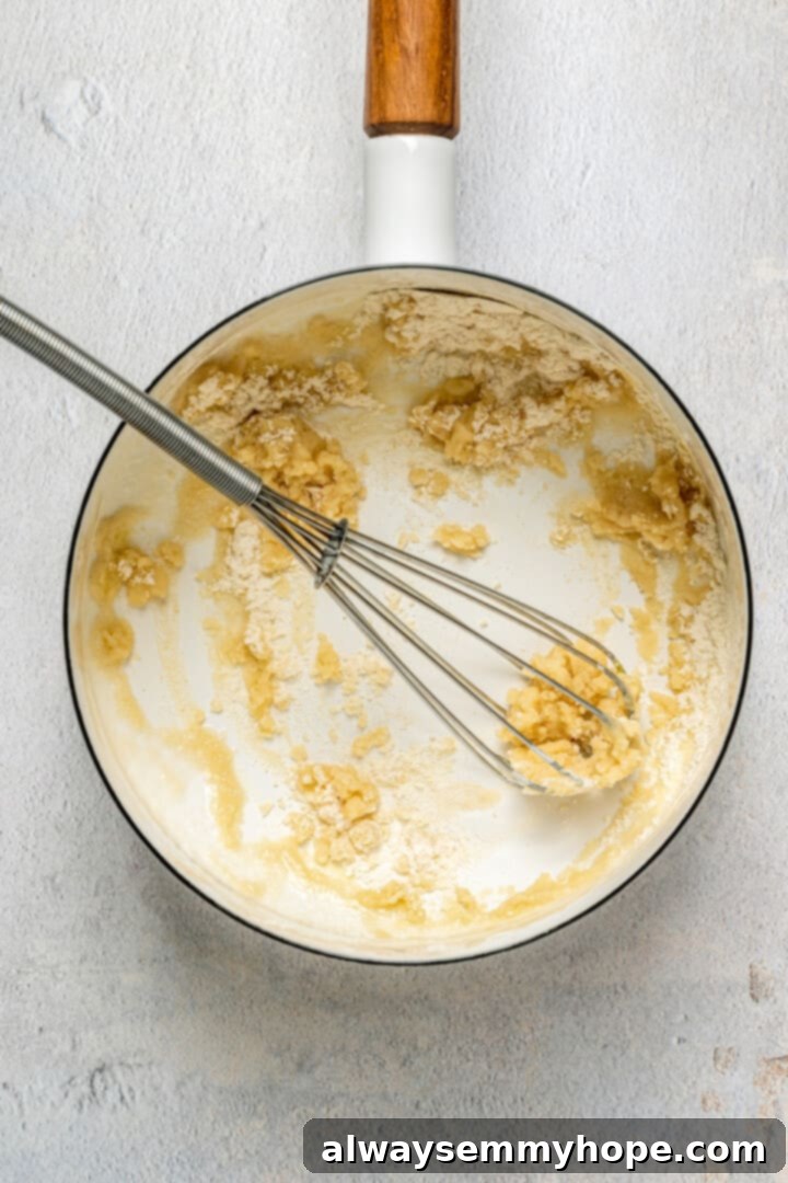 This vegan breakfast pizza features plant-based eggs, cheese, hash browns, and sausage, all baked on a crispy, chewy crust. So good! A small saucepan on a stovetop, showing melted vegan butter and flour being whisked together to form a roux.