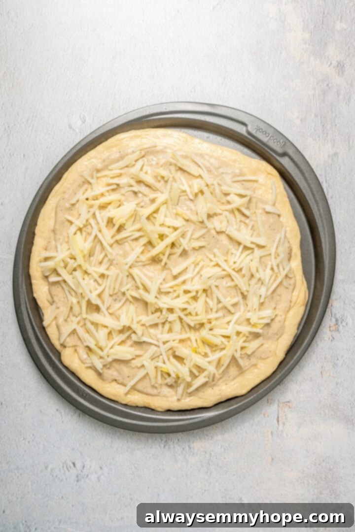 This vegan breakfast pizza features plant-based eggs, cheese, hash browns, and sausage, all baked on a crispy, chewy crust. So good! A vegan breakfast pizza crust, evenly spread with gravy and topped with a layer of frozen diced potatoes.