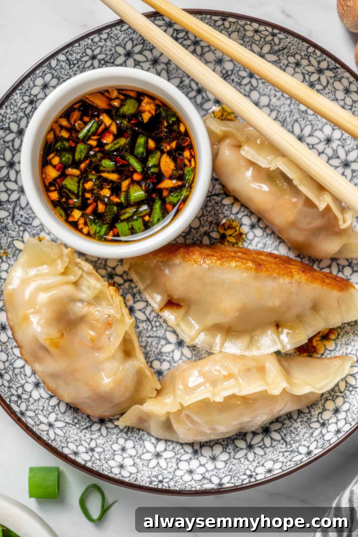 Overhead view of vegan dumplings on plate with dipping sauce and chopsticks