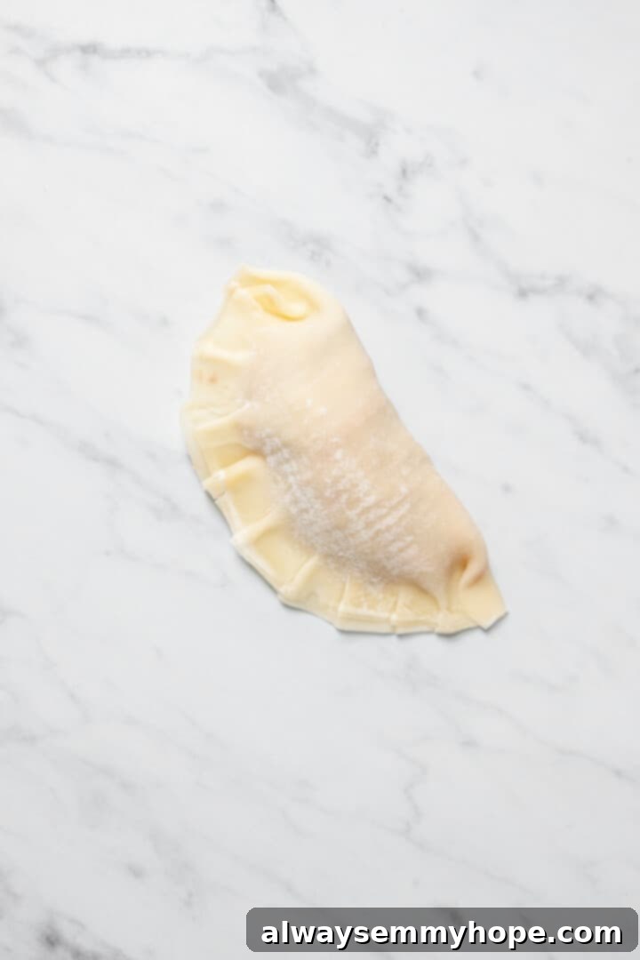 Overhead view of dumpling with crimped edges on marble work surface