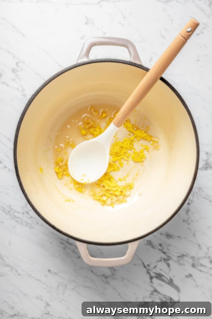 Overhead view of garlic, ginger, and oil in Dutch oven with spoon