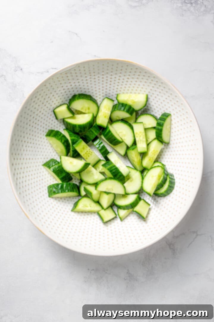 Crisp cucumbers and sun-ripened tomatoes are tossed in a simple vinaigrette for a refreshing, flavourful vegan cucumber and tomato salad. Overhead view of freshly sliced cucumber pieces arranged in a bowl, ready for the salad.