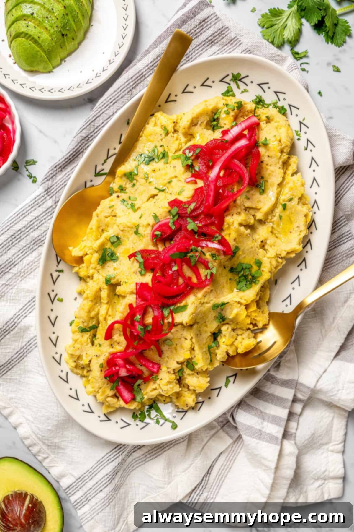 Overhead view of platter of vegan mangú topped with vibrant pickled red onions and fresh cilantro, ready to be served for a delicious Dominican breakfast.