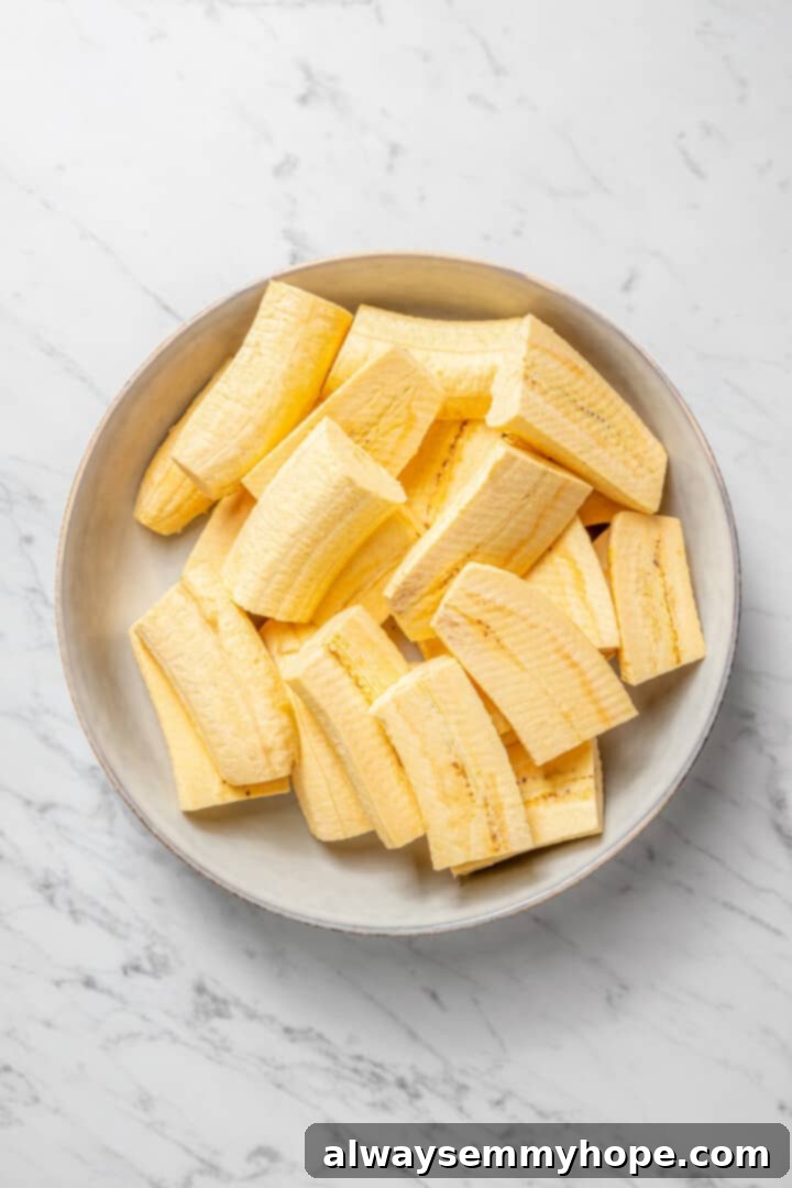 Overhead view of green plantains precisely cut into pieces, ready for cooking.