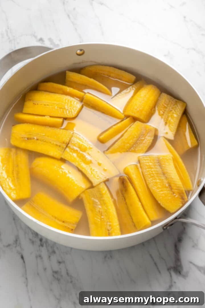 Plantains and water in a pot, simmering gently on the stovetop as they cook to tenderness for the mangú recipe.