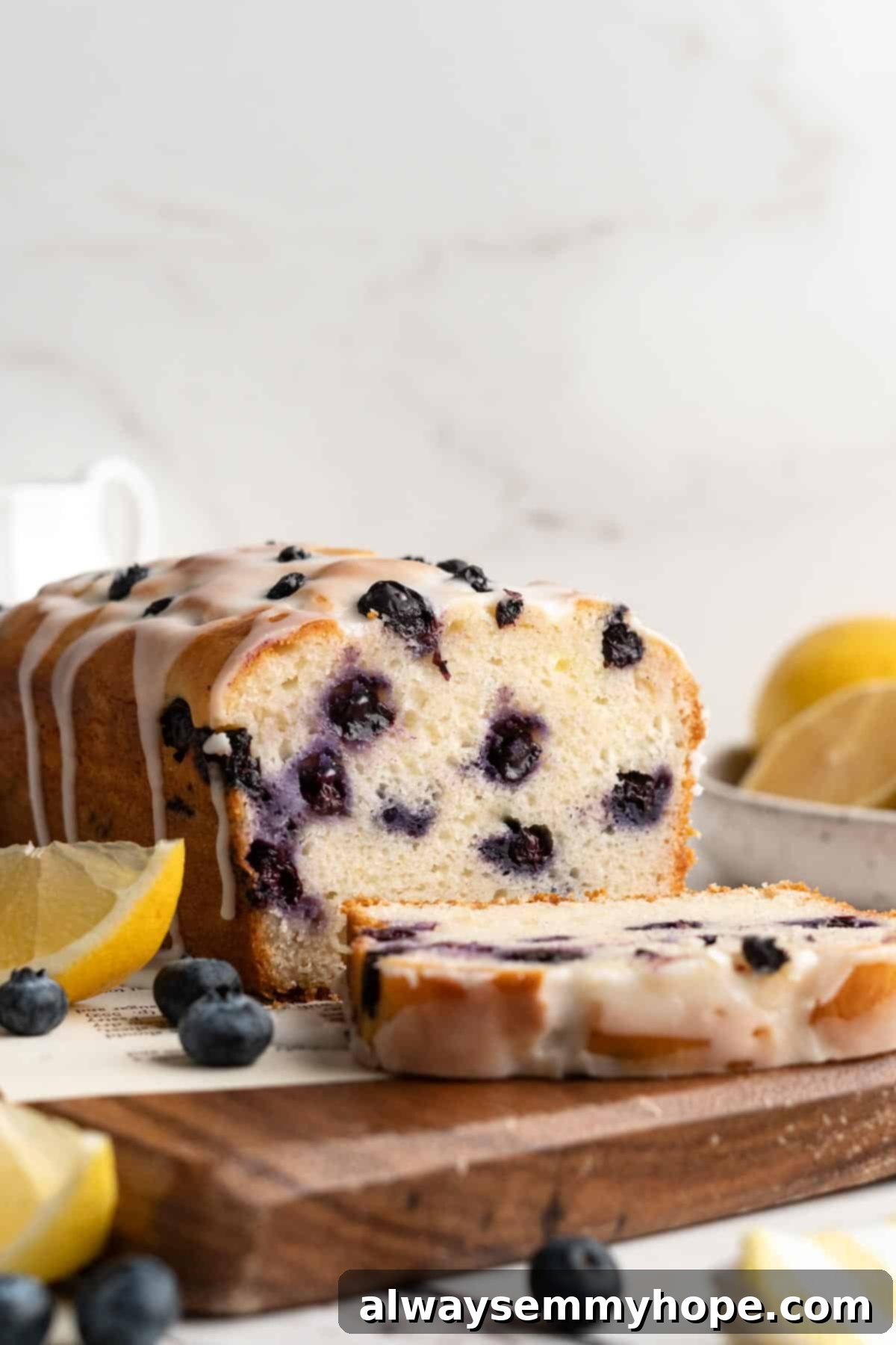 Vegan lemon blueberry bread on a wooden board with one slice cut, ready to be served.